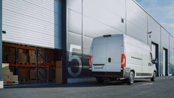 istock Outside of Logistics Retailer Warehouse With Manager Using Tablet Computer, Workers Start Loading Delivery Truck with Cardboard Boxes. Online Orders, Purchases, E-Commerce Goods. High Angle Shot 1340887545