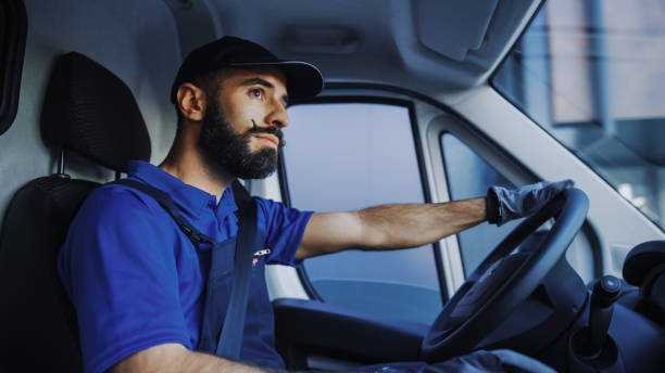 Portrait of Stylish Latin Delivery Truck Driver on the Road. Happy Professional Carefully Driving, Delivering Online Orders, E-Commerce Goods, Food, Medicine. Frontline Hero Doing Job. Inside Vehicle retrato del elegante conductor de camión de reparto latino en la carretera. feliz profesional conduciendo cuidadosamente, entregando pedidos en línea, productos de comercio electrónico, alimentos, medicinas. héroe de primera línea haciendo el trabajo.