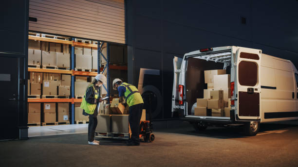 istock Outside of Logistics Retailer Warehouse With Female Manager Using Tablet Computer, Worker Loading Delivery Truck with Cardboard Boxes. Online Orders, Purchases, E-Commerce Goods, Supply. 1340887669