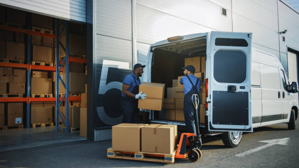 Outside of Logistics Distributions Warehouse: Two Workers Talk, Joke use Hand Pallet Truck Start Loading Delivery Truck with Cardboard Boxes, Online Orders, Purchases, E-Commerce Goods. Outside of Logistics Distributions Warehouse: Two Workers Talk, Joke use Hand Pallet Truck Start Loading Delivery Truck with Cardboard Boxes, Online Orders, Purchases, E-Commerce Goods. logistical stock pictures, royalty-free photos & images