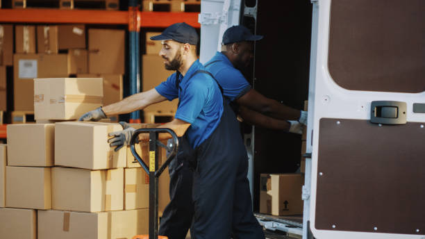 istock Outside of Logistics Distributions Warehouse: Diverse Team of Two Workers Talk, Joke Around Loading Delivery Truck with Cardboard Boxes, Online Orders, Medicine, Food Supply, E-Commerce Goods 1340887694