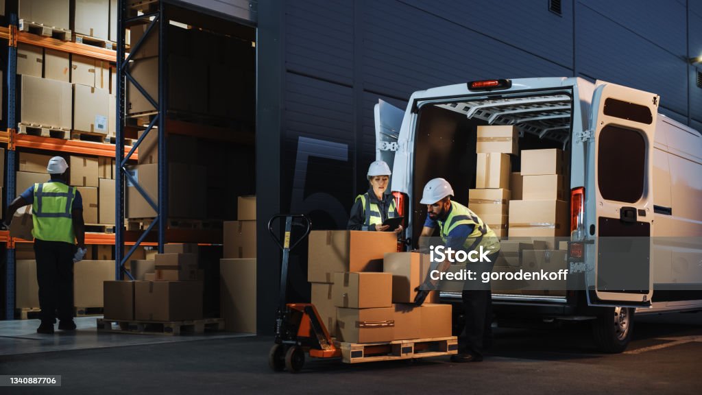Outside of Logistics Retail Warehouse With Inventory Manager Using Tablet Computer, talking to Worker Loading Delivery Truck with Cardboard Boxes, Online Orders, Food and Medicine Supply, E-Commerce Freight Transportation Stock Photo