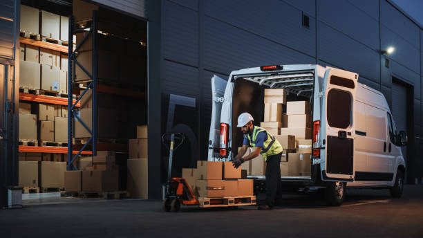 Outside of Logistics Distributions Warehouse Delivery Van: Worker Unloading Cardboard Boxes on Hand Truck, Online Orders, Purchases, E-Commerce Goods, Food, Medical Supply. Evening Shot Outside of Logistics Distributions Warehouse Delivery Van: Worker Unloading Cardboard Boxes on Hand Truck, Online Orders, Purchases, E-Commerce Goods, Food, Medical Supply. Evening Shot logistical stock pictures, royalty-free photos & images