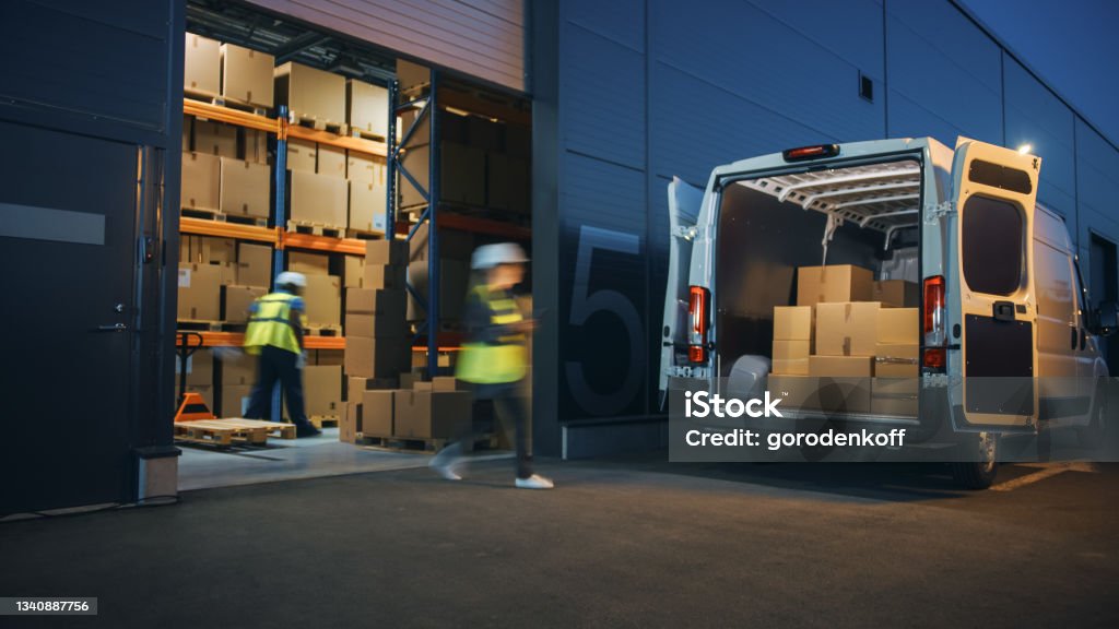 Outside of Logistics Distributions Warehouse Diverse Team of Workers Loading Delivery Truck with Cardboard Boxes. Online Orders, Purchases, E-Commerce Goods, Supply Chain. Blur Motion Shot. Freight Transportation Stock Photo