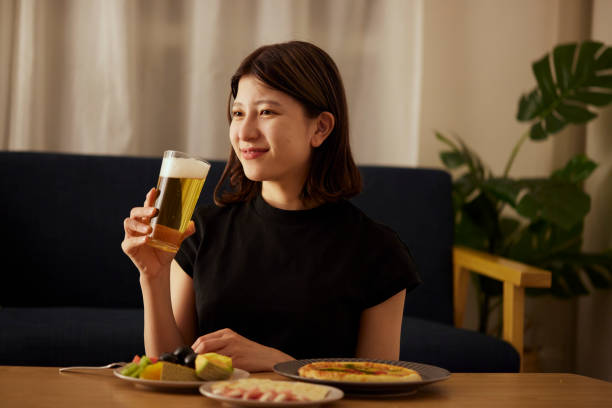 A young Japanese woman enjoying alcohol alone at home A young Japanese woman enjoying alcohol alone at home woman drinking beer stock pictures, royalty-free photos & images