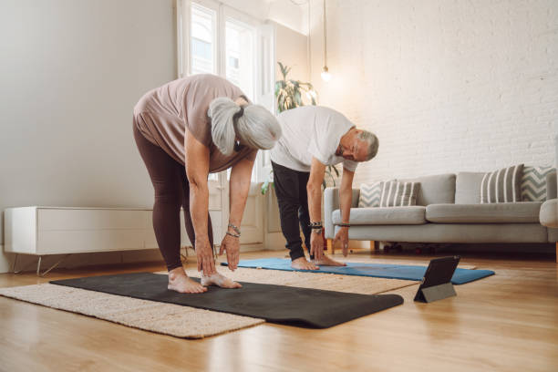 starsza para uprawia jogę w domu - healthy lifestyle yoga vitality flexibility zdjęcia i obrazy z banku zdjęć