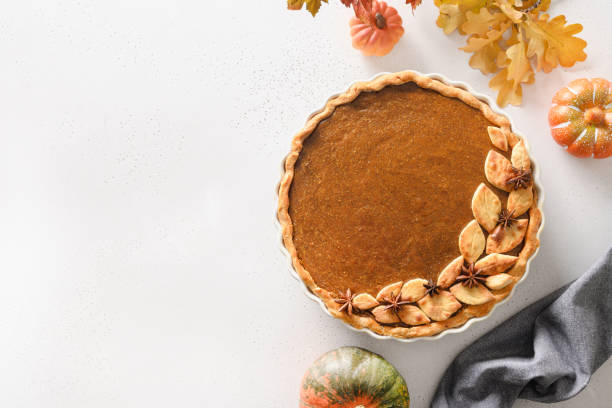 Homemade tasty pumpkin pie with autumn decorations and leaves for Thanksgiving Day on white. Homemade seasonal pumpkin pie with spices,cinnamon,cardamom, ginger for Thanksgiving Day on white background with copy space. View from above. pumpkin pie stock pictures, royalty-free photos & images