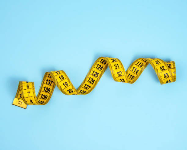 istock Yellow spiral tape measure on blue bright background 1340892874