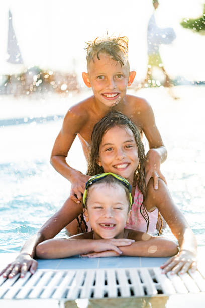 istock Brothers and sister having fun in swimming pool 1340893095