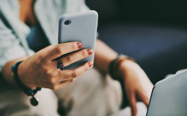istock Cropped shot of an unrecognisable woman sitting alone on her sofa at home while using her laptop and cellphone 1340894167
