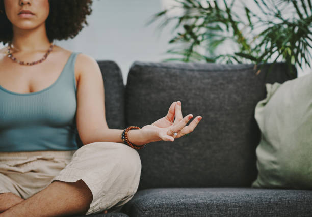 Cropped shot of an unrecognisable woman sitting alone on her sofa at home and meditating Connecting with my higher self mudra stock pictures, royalty-free photos & images