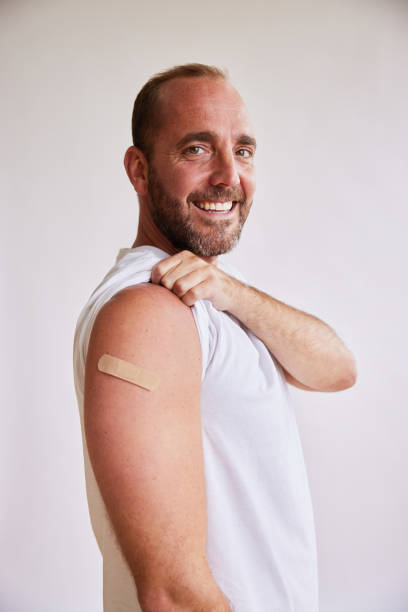 istock Smiling man with a bandage on his arm after a Covid-19 vaccination 1340896611