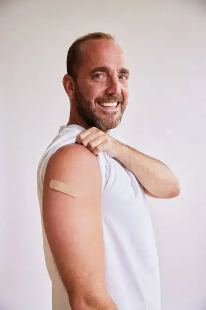 Photo of Smiling man with a bandage on his arm after a Covid-19 vaccination