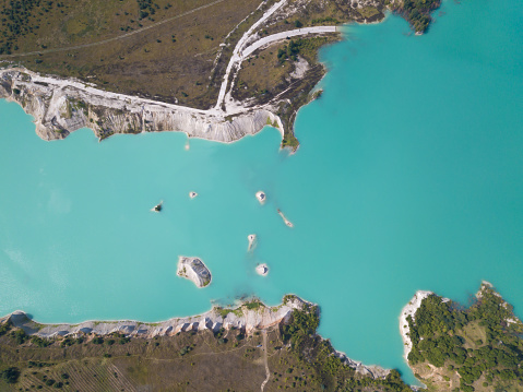 Man-made mountains formed during the extraction of chalk. Artificial lake in a chalk quarry with turquoise water in the summer season in the open air near Krichev, Belarus, top view