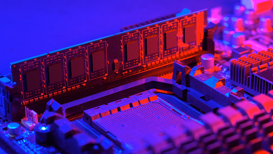 Random access memory strip inserted into the motherboard. Motherboard out-of-the-box red-blue light. Computer components