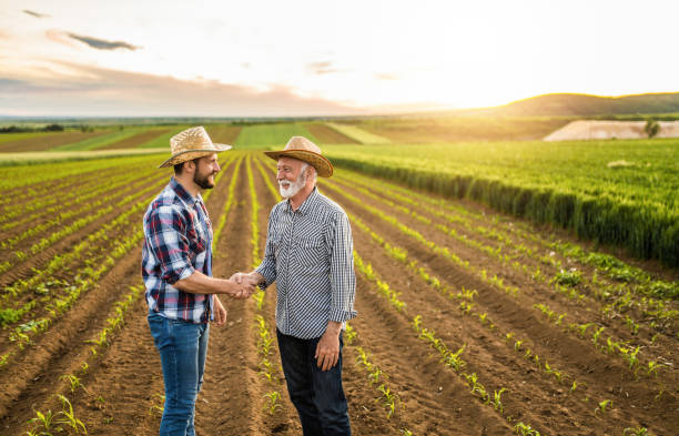 istock Two happy farmers shaking hands on an agricultural field. 1340905723