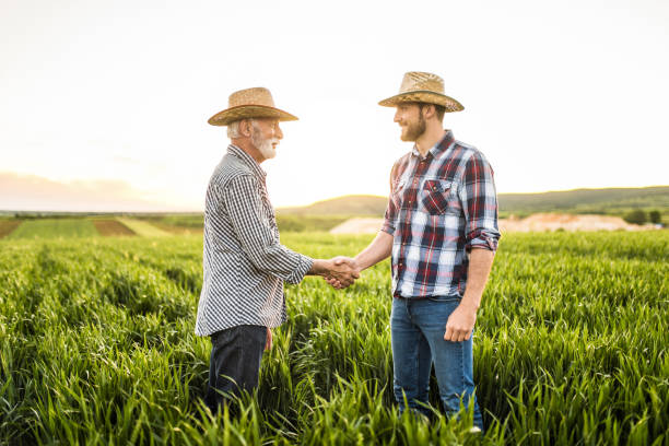 istock Two happy farmers shaking hands on an agricultural field. 1340905862