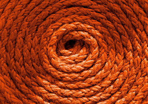 Abstract background of vivid orange rust brown colour boat or ships rope forming repeated circles idea for marine backdrops. Outdoors marine vessel ships old rope nautical equipment. Concept shapes and forms copy space.