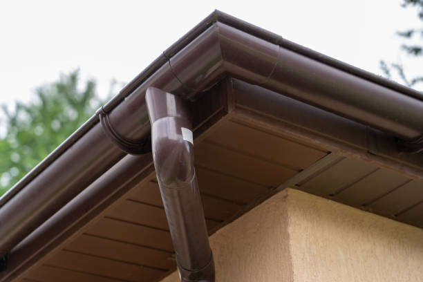 istock Brown plastic gutter system against sky, roof overhang 1340916880