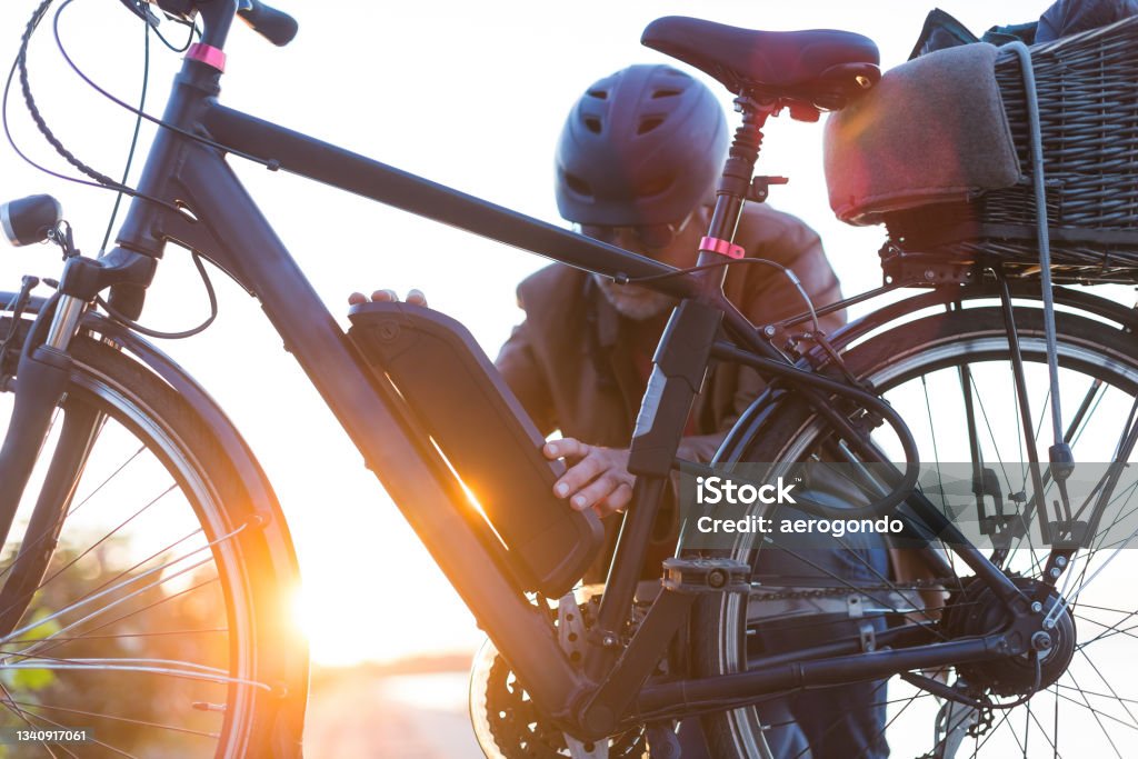man changing electric bicycle battery biker inserting electric bike battery Electric Bicycle Stock Photo