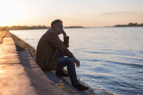 istock lonely man sitting on the river bank 1340917067