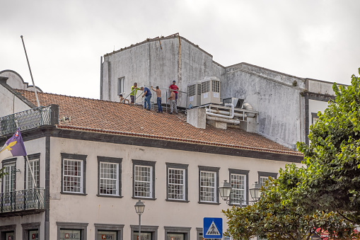 Group of men working on a roof in Ponta Delgada which is the main city on the Portuguese Azorean Island San Miguel in the center of the North Atlantic Ocean.