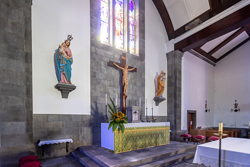 View to the altar with a crucifix in Igreja De Nossa Senhora da Alegria church in the town Furnas on the Portuguese Azorean Island San Miguel in the center of the North Atlantic Ocean. It is a modern church, build in 1960.