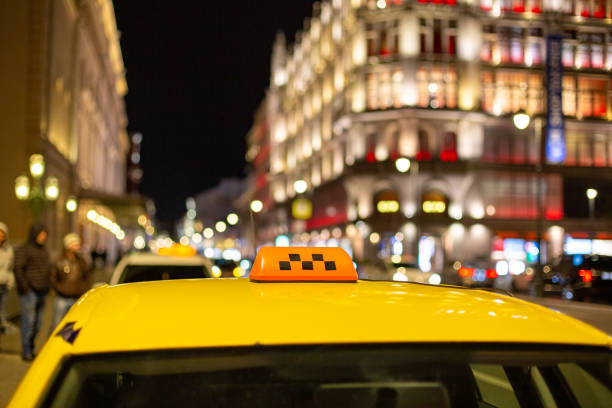 el gran letrero de taxi en el fondo de la ciudad nocturna - taxi fotografías e imágenes de stock