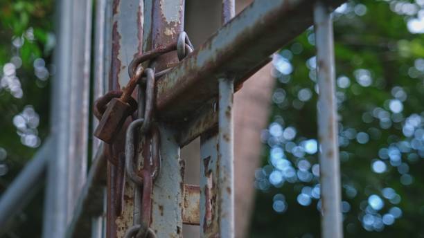 istock Closed Rusty Metal Gate Secured with Iron Chain and Simple Padlock 1340920055