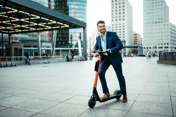 Commuter using e-scooter in the city Millennial businessman in full suit or businesswear in Berlin, Germany push scooter stock pictures, royalty-free photos & images