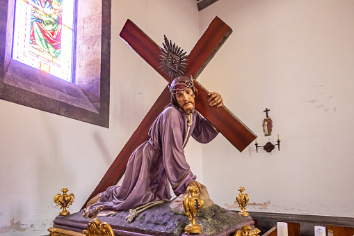 Figure of the suffering Jesus Christ with the cross in Igreja De Nossa Senhora da Alegria church in the town Furnas on the Portuguese Azorean Island San Miguel in the center of the North Atlantic Ocean. It is a modern church, build in 1960.