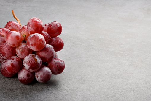 Bunch of red grapes on the gray color stone texture with copy space
