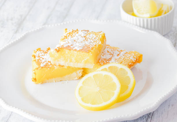 istock Light and airy lemon bars with lemon slices on white plate and white wood table 1340934874