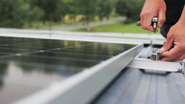 Photo of Mounting solar panel, installing solar panels on the roof of the house. Connection of solar panels. Close up of worker installing and working on maintenance of photovoltaic panel system installed