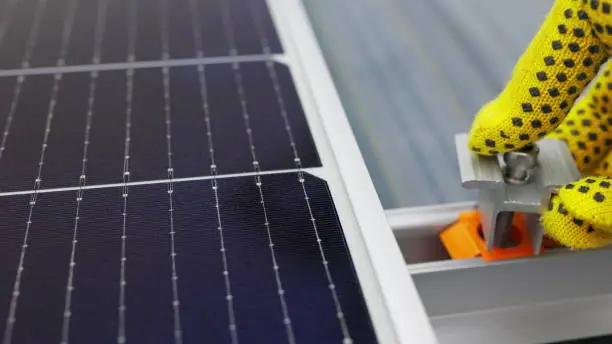 Photo of Mounting solar panel, installing solar panels on the roof of the house. Connection of solar panels. Close up of worker installing and working on maintenance of photovoltaic panel system installed