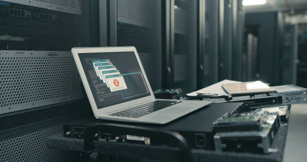 scatto di un laptop con un messaggio di errore sullo schermo in una sala server vuota - computer network server repairing technology foto e immagini stock