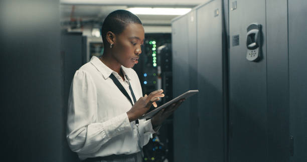 foto de una mujer joven usando una tableta digital mientras trabajaba en un centro de datos - computer programmer network server data center fotografías e imágenes de stock