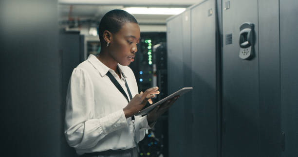 scatto di una giovane donna che utilizza un tablet digitale mentre lavora in un data center - computer network server repairing technology foto e immagini stock