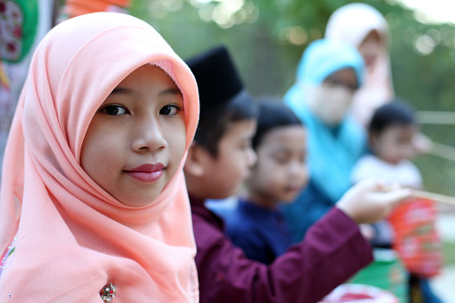 A group of Muslim girls and boys are enjoying playing with Chinese lanterns.