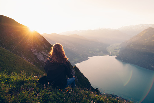 La excursionista femenina se relaja en la cresta de la montaña al amanecer photo