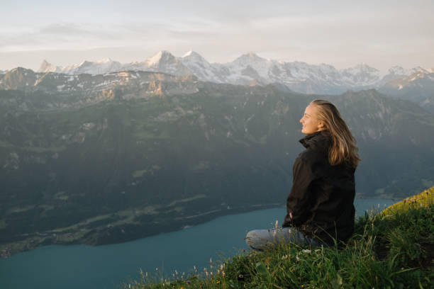 female hiker relaxes on mountain ridge at sunrise - switzerland lake mountain landscape imagens e fotografias de stock