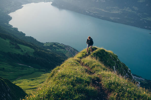 istock Young man hikes up mountain ridge, at sunrise 1340942675