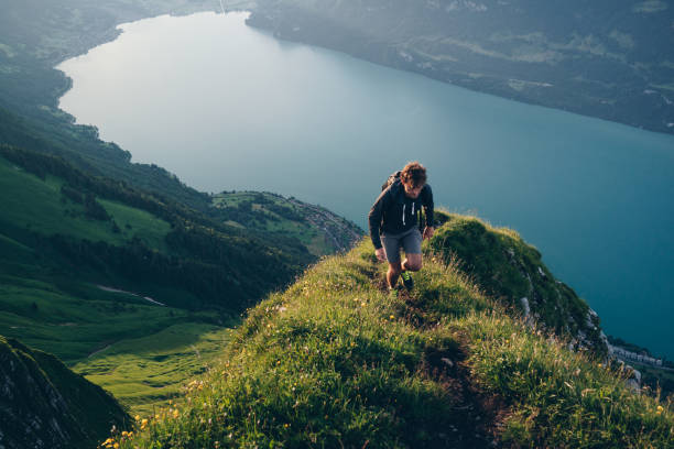 istock Young man hikes up mountain ridge, at sunrise 1340942691