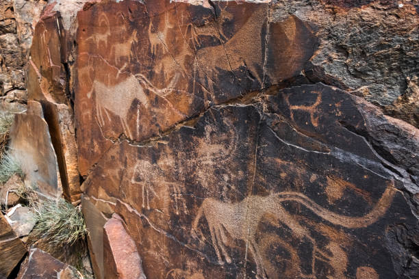 istock Ancient cave paintings on rocks. Bronze Age, Iron Age and Middle Age rock art. Tanbaly tas petroglyphs in Kazakhstan. 1340942785