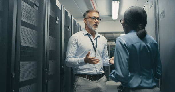 istock Shot of a man and woman having a discussion in a data centre 1340944036