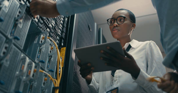 scatto di un uomo e di una donna che utilizzano un tablet digitale mentre lavorano in un data center - data center network server computer network foto e immagini stock