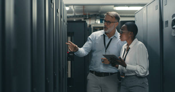 scatto di un uomo e di una donna che utilizzano un tablet digitale mentre lavorano in un data center - computer network server repairing technology foto e immagini stock