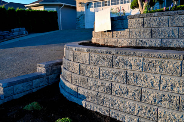 Retaining Wall A close-up view from the side looking at the return of a two tier retaining wall returning in a curve back into the hill in gray color back lit by early morning sunlight. hardscape photos stock pictures, royalty-free photos & images
