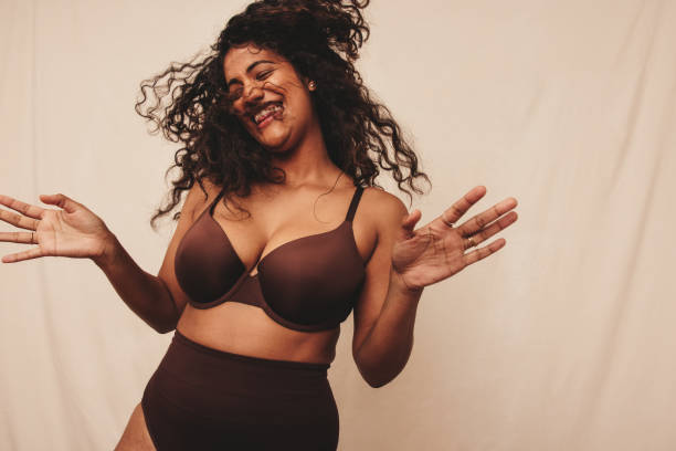 Filled with happiness and positive vibes Filled with happiness and positive vibes. Happy young woman laughing cheerfully while standing against a studio background. Body positive young woman embracing her natural self. body confidence stock pictures, royalty-free photos & images