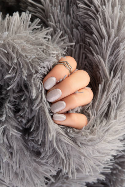 istock Manicured womans hand holding furry gray fabric 1340944341
